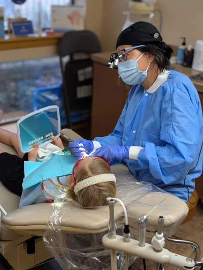 Pediatric dentistry patient looking at herself in the mirror at Beelman Dental