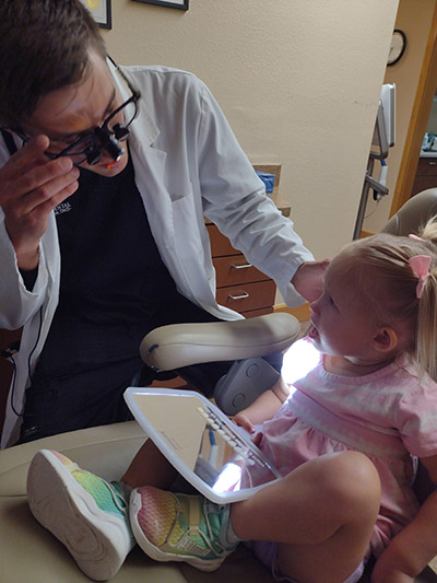 Dr. Beelman showing a pediatric patient his dental tools during her appointment